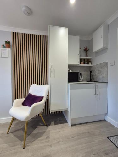 a kitchen with a white chair and a counter at Pro Stay Studio in Fort William