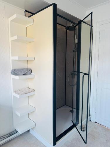 a glass shower in a bathroom with shelves at Appartement cosy et lumineux Gravelines centre la gravelinoise 2 in Gravelines