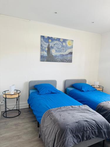 a bedroom with two beds and a painting on the wall at Appartement cosy et lumineux Gravelines centre la gravelinoise 2 in Gravelines