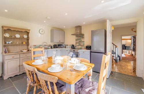 eine Küche mit einem Holztisch mit Stühlen und einem Kühlschrank in der Unterkunft Prince Rupert's cottage with garden in Sibbertoft