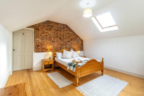 ein Schlafzimmer mit einem Bett und einer Ziegelwand in der Unterkunft Prince Rupert's cottage with garden in Sibbertoft