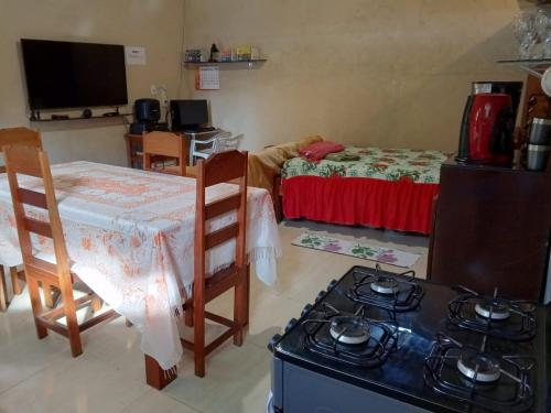 una cocina con fogones, una mesa y una cama en Quarto completo, en Ananindeua