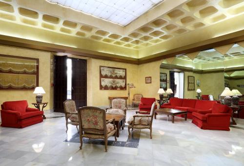 a lobby with red couches and a table and chairs at Crisol Monasterio de San Miguel in El Puerto de Santa María