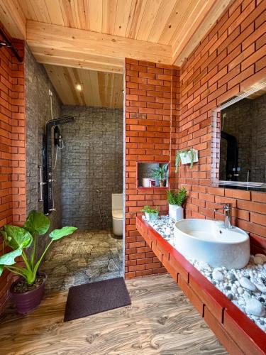 La salle de bains est pourvue d'un lavabo et d'un mur en briques. dans l'établissement The Palace Eco Cottage, à Ella