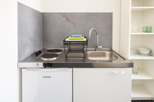 een keuken met witte kasten en een spoelbak bij Business Apartments Augsburg mit WIFI, TV, Parken in Augsburg