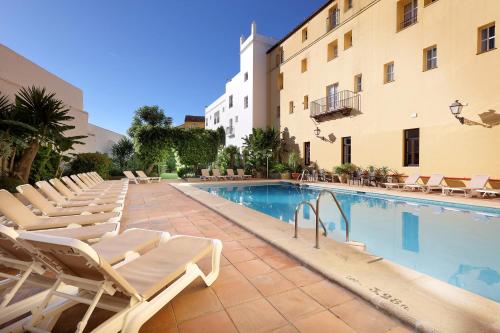 a swimming pool with lounge chairs next to a building at Crisol Monasterio de San Miguel in El Puerto de Santa María