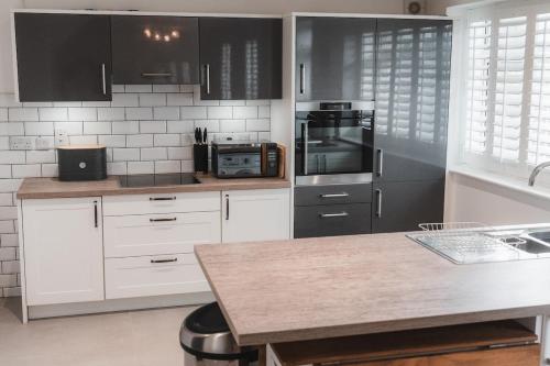 a kitchen with white cabinets and black appliances at Charming 2-Bed House by Brookland Stays in Jersey Free Wi-Fi & Parking Included 