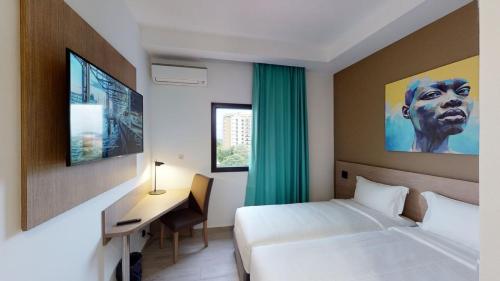a hotel room with two beds and a desk and a monitor at Aichti Hotel in Abidjan
