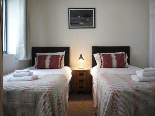 a bedroom with two beds and a table with a lamp at Deluxe Seaside Flat easy access in Westward Ho