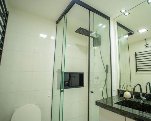 Vila BalneáriaにあるApto com Ar-condicionado e Churrasqueira Privativaのガラスのシャワーと洗面台を備えたバスルーム