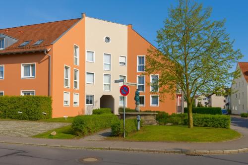 ein orange-weißes Gebäude mit einem Baum und einem Straßenschild in der Unterkunft SUNNYHOME Monteurwohnungen und Apartments in Schwandorf in Schwandorf in Bayern