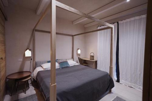 a bedroom with a canopy bed and a table at Borgo Lianti case vacanza Sardegna in San Pasquale