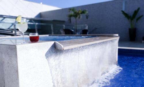 een glas wijn op een randje naast een zwembad bij Good Stone Curvelo Hotel in Curvelo