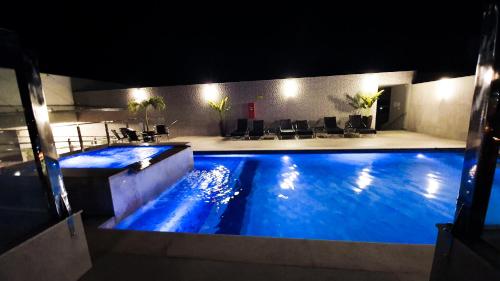 een groot zwembad met 's nachts blauw water bij Good Stone Curvelo Hotel in Curvelo