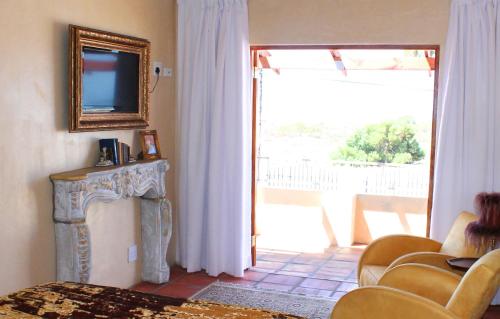 a living room with a television and a door to a patio at Goblin's Inn in Stompneusbaai