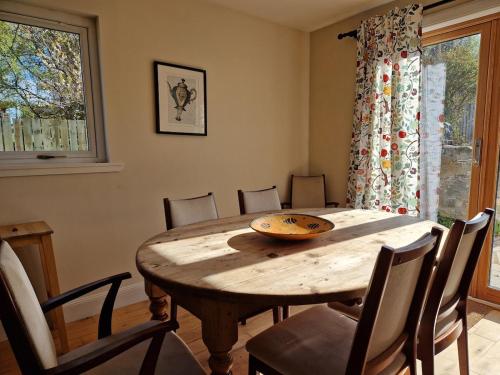 ein Esszimmer mit einem Holztisch und Stühlen in der Unterkunft Highland River Cottage with Hot Tub in Evanton