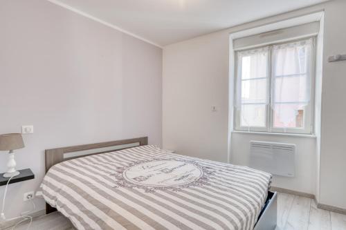 Una cama en una habitación blanca con ventana. en Le Confort du Soir - T2 - Lagnieu, en Lagnieu