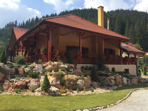 ein Haus mit einer Veranda auf einem Hof in der Unterkunft Lacu Roșu Mountain Lodge in Lacul Roşu