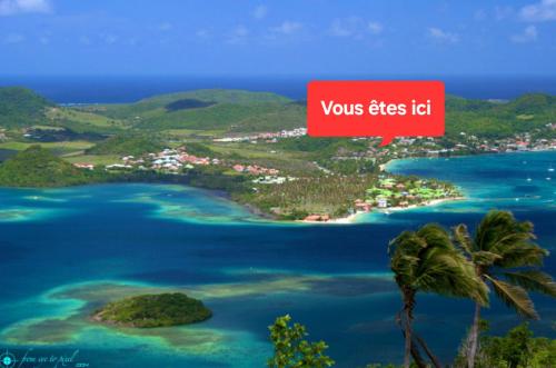 an island in the ocean with a red sign that reads yours bites id at Les Villas Créoles de Sainte-Anne in Sainte-Anne