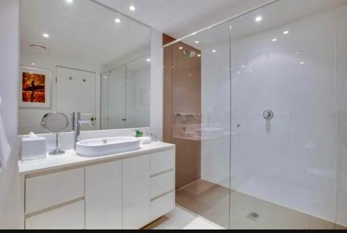 Un baño blanco con lavabo y ducha en Level 15 - Hilton Surfers Paradise, en Gold Coast