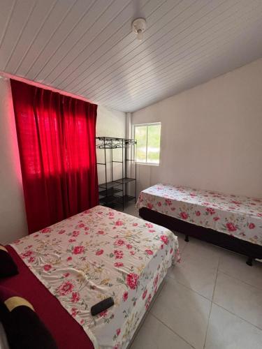 ein Schlafzimmer mit zwei Betten und einem roten Vorhang in der Unterkunft Summer House in Jijoca de Jericoacoara