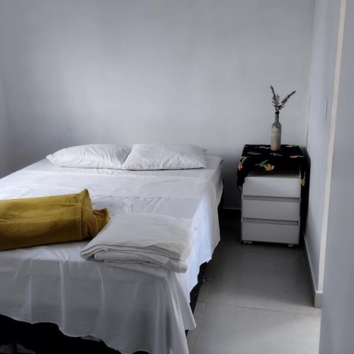 une chambre avec un lit blanc et une table de chevet dans l'établissement Estúdio Vênus, à Alto Paraíso de Goiás