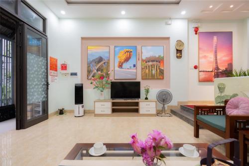 a living room with a tv and paintings on the wall at AnhHouse85 Da Nang - 750 meters from the beach - Free airport pick up and free modern coffee machine provided in Da Nang