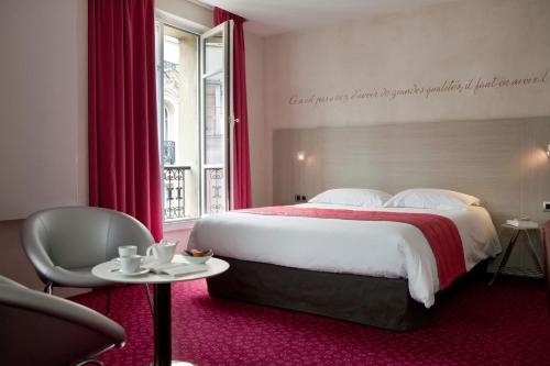 a hotel room with a large bed and a table at Hôtel de Sévigné in Paris