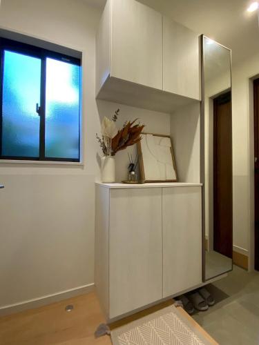 a white cabinet in a room with a window at 一軒家貸切尾道観光 JR松永駅徒歩1分MAX6人 Cozy Entire House Great for Onomichi Sightseeing! 1-Min Walk from JR Matsunaga Station, Free Parking, Sleeps up to 6 Guests in Fukuyama