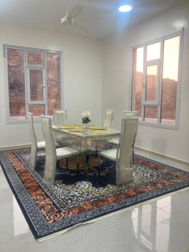 a dining room with a table and chairs on a rug at Sunset view of Jebel Shams in Misfāh