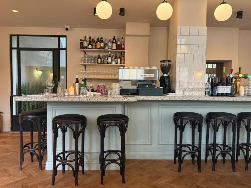een bar met zwarte barkrukken aan een toonbank bij Hotel Bleecker by BHC in Bloemendaal