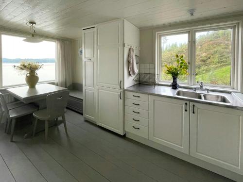 a kitchen with white cabinets and a sink and a table at Romantic Summer House On Orust in Stillingsön