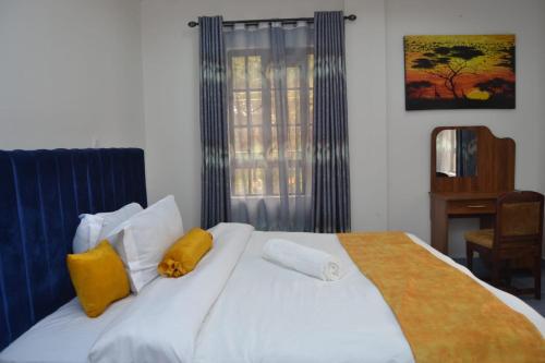ein Schlafzimmer mit einem großen weißen Bett mit gelben Kissen in der Unterkunft White House II in Naivasha