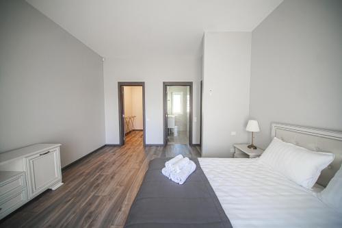 ein weißes Schlafzimmer mit einem Bett und Holzböden in der Unterkunft Kintu Perlas Villa - with optional Hot Tub on request in Kintai