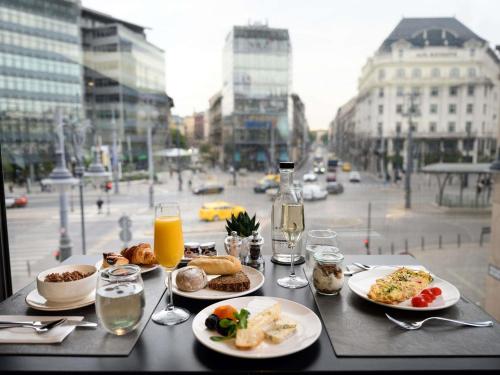 a table with plates of food and glasses of orange juice at Mercure Budapest Korona in Budapest