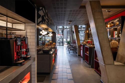 un restaurante con un largo pasillo con mesas y sillas en Radisson RED Hotel V&A Waterfront Cape Town, en Ciudad del Cabo