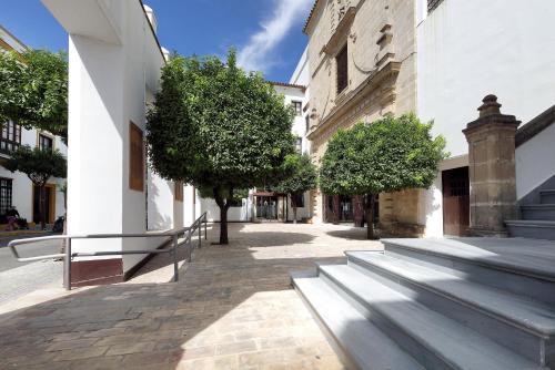 a group of benches next to a building with trees at Crisol Monasterio de San Miguel in El Puerto de Santa María
