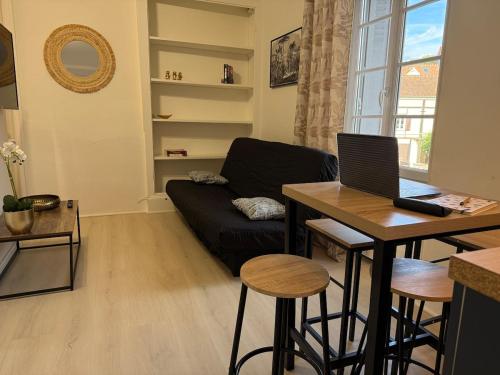 een woonkamer met een bank en een tafel met een laptop bij SWEET HOME Votre havre de paix au cœur d'Epernon in Épernon
