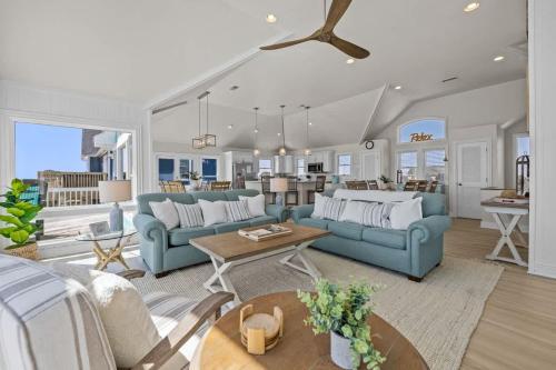 a living room with two blue couches and a kitchen at Blue Moon - LUX Oceanfront Pool Hot Tub Theater in Waves