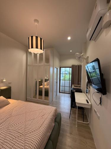 a bedroom with a bed and a desk and a television at สุขใจ โฮม Minimal Apartment ใกล้ Central นครปฐม แอร์เย็นฉ่ำๆ in Nakhon Pathom