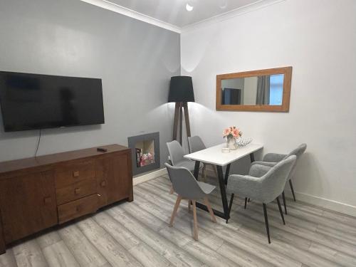 a living room with a table and chairs and a television at 2B apartment near Glasgow SEC, OVO Hydro & city centre in Glasgow