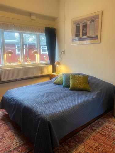 a bedroom with a bed with blue sheets and windows at Vallby Herrgård in Mariestad