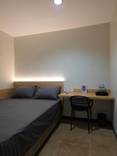 a bedroom with a bed and a desk with a chair at Hello Inn permata hijau in Stasiun Tawang