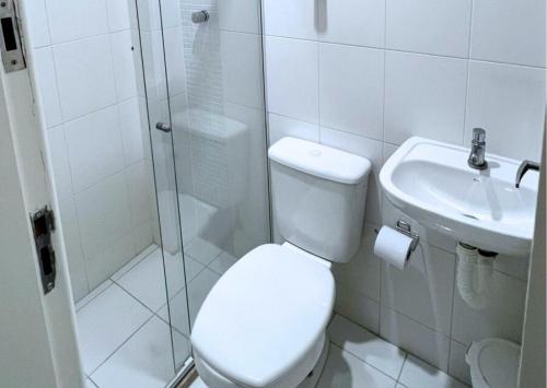 a bathroom with a toilet and a shower and a sink at RefugioBacutia- Prédio FRENTE MAR Bacutia- 6 pessoas- 3 Quartos com AR sendo 1 suite - varanda- sala de estar e jantar Ampla -Piscina e Sauna no Prédio in Guarapari