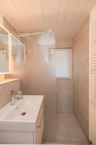 a white bathroom with a sink and a shower at Mätzwiesen Höckli - CharmingStay in Flumserberg