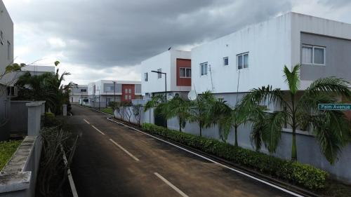 an empty street next to a white building with palm trees at The Elegant 3BedRoom Home in Community 25, Tema in Dawhwenya