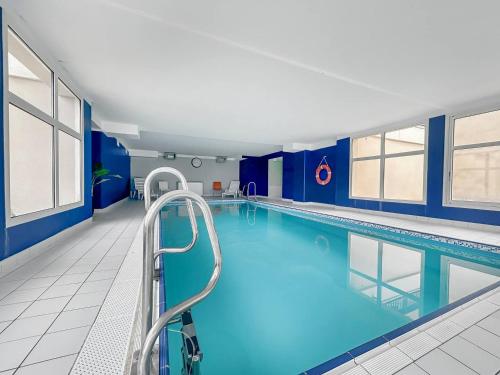 une grande piscine avec une main courante dans un bâtiment dans l'établissement Gîte Le 47, à Levernois