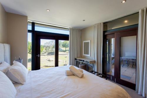 ein Schlafzimmer mit einem großen weißen Bett und einem Balkon in der Unterkunft Terrace Tranquility at Oubaai Golf Estate in Herolds Bay