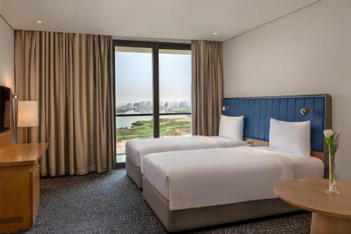 two beds in a hotel room with a view at Yas Plaza Bay by IHG in Abu Dhabi