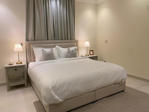 a bedroom with a large white bed with two night stands at شقة بغرفتي نوم وغرفة معيشة in Jeddah